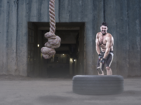 Athlete without shirt hitting a tire with a sledgehammer on the streetの写真素材