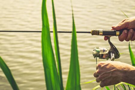 Fisherman start to fishing by spinning on river in sunny weather