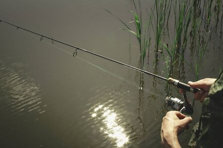 Fisherman start to fishing by spinning on river in sunny weather