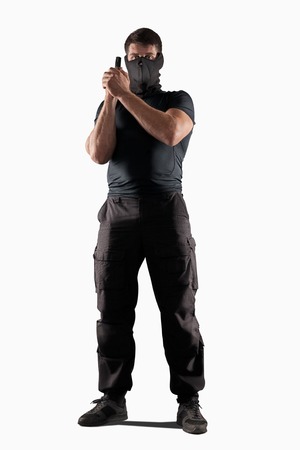 man in black uniform and headgear with gun in prepared position isolated on white backgroundの写真素材