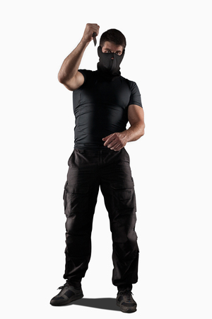 Man in black uniform attacking with knife isolated on whiteの写真素材
