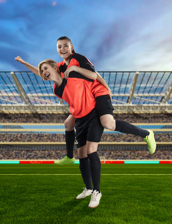 two female soccer players celebrating victory on soccer filedの写真素材