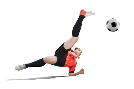 Female football player in orange uniform making Bicycle kick isolatedの写真素材