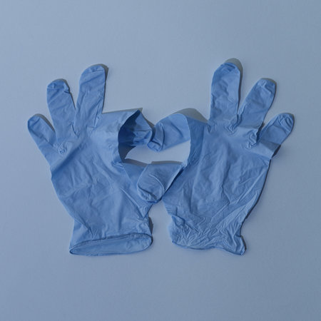 Heart made of blue virus protective gloves on bright blue