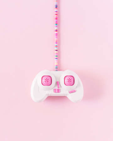 Pink joystick with colorful cable on soft pastel pink background. Minimalistic flat lay.