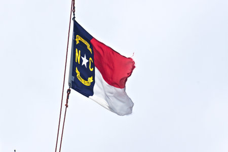 A torn and tattered North Carolina State Flag blows in the wind.の写真素材