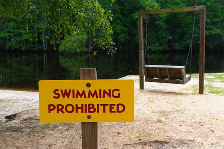 A No Swimming sign next to the river in Lumber River State Park.の写真素材