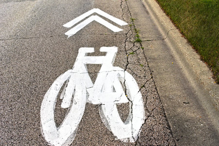A white bike lane symbol is painted on a local road to promote safe sharing of the road.
