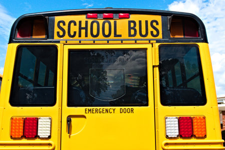 A view of the back of a yellow school bus showing the emergency door exit.