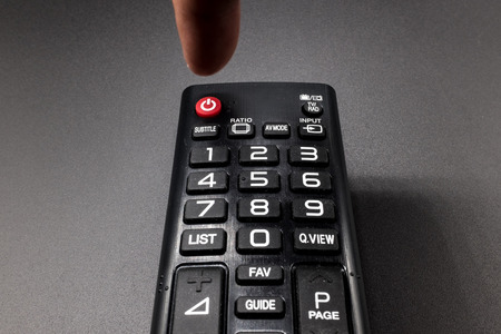 Pressing the power button on the remote controlの写真素材