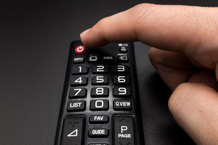 Pressing the power button on the remote controlの写真素材