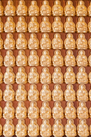 Many small Buddha statue on the wall at chinese temple, Thailandの写真素材