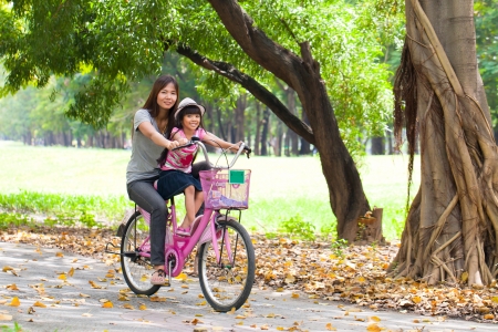 Mother and a daughter cycling bicycle at the parkの写真素材