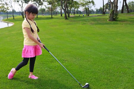 Little girl just swing golf ball on golf course fairwayの写真素材