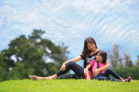 Mother and daughter relaxing sitting grassの写真素材