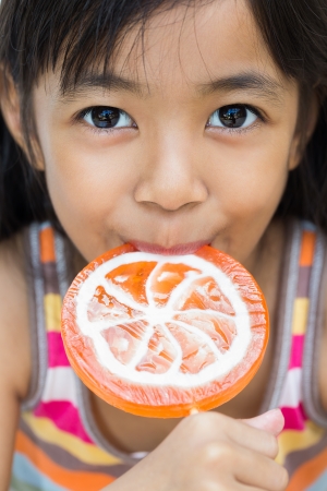 Closeup smiling little girl with a lollipopの写真素材