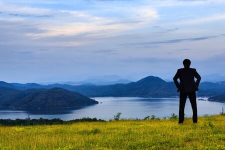 Businessman standing on a green grass in the mountains