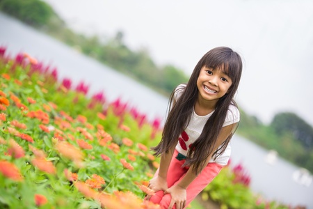 Asian little girl standing with hands on knees in a meadow, Outdoor portraitの写真素材