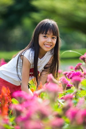 Asian little girl standing with hands on knees in a meadow, Outdoor portraitの写真素材