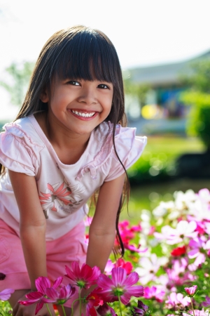 Asian little girl standing with hands on knees in a meadow, Outdoor portraitの写真素材