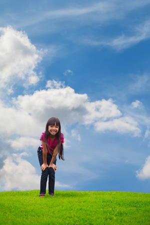 Smiling asian little girl standing on green grass, Outdoor Portraitの写真素材