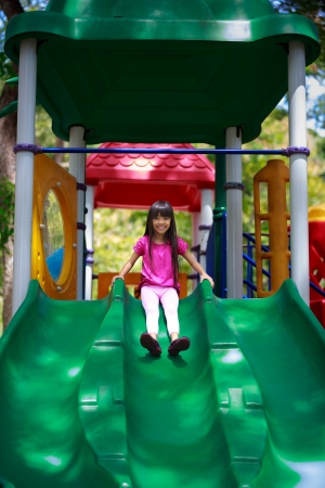 Smiling asian little girl sitting slide, Outdoor portraitの写真素材