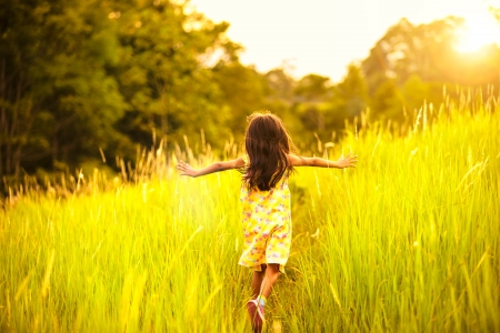 Little girl running on meadow with sunsetの写真素材