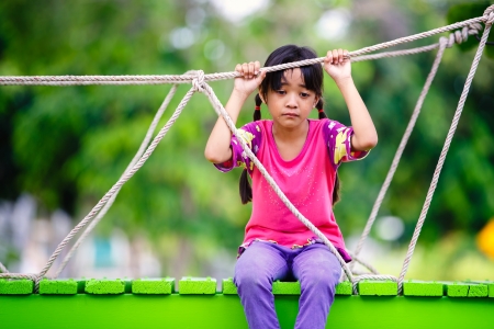 Crying little asian girl sitting alone on a playground, Outdoorの写真素材