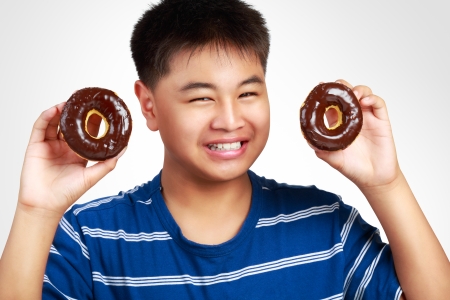 Little asian boy holding a chocolate donuts, Isolated on white backgroundの写真素材