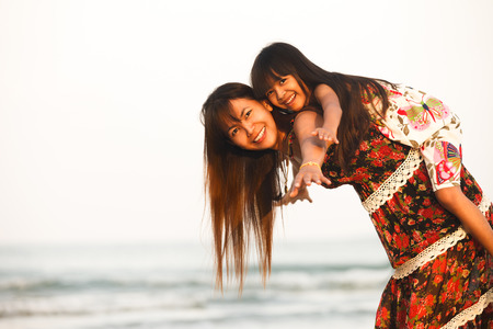 Happy mother holding her daughter on the beachの写真素材