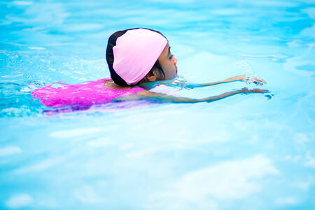 Little asian girl on swimming pool blue water backgroundの写真素材