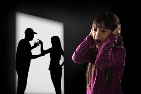Crying illtle asian girl with her fighting parents in the backgroundの写真素材