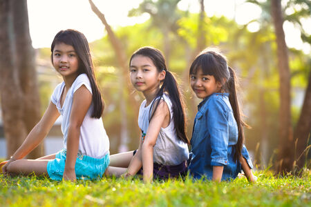 Cute girls seated on green grass and relaxingの写真素材