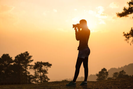 Photographer female taking a picture with the sun behindの写真素材