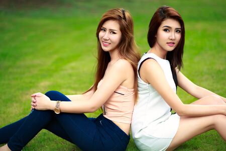 Two young asian women in park having good timeの写真素材