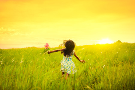 Little girl running on meadow with sunsetの写真素材