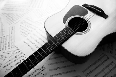 Acoustic guitar laying across sheet music, Black  White toneの写真素材