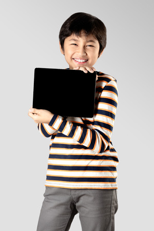 Young boy with digital tablet, Isolated on grey backgroundの写真素材
