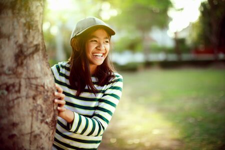 Laughing young girl enjoying her time outside in park with sunset in backgroundの写真素材