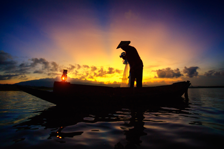 Fisherman on a lake from the boat at sunriseの写真素材