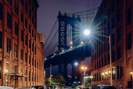 Brooklyn bridge seen from a narrow alley enclosed by two brick buildings at dusk, NYC USAの写真素材