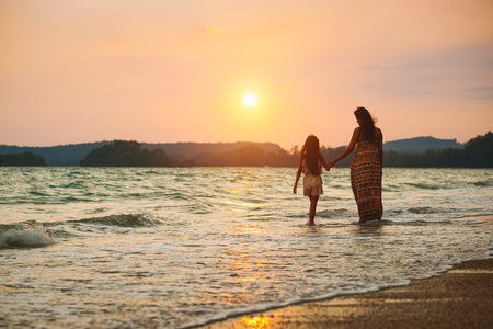 Mother and daughter walking on the beach with sunset, Krabi Thailandの写真素材