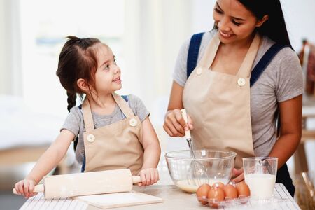 Mother and daughter using a rolling pin together in the kitchenの写真素材