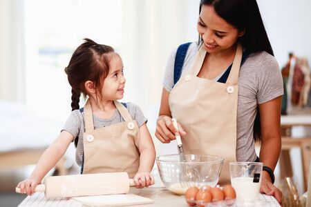 Mother and daughter using a rolling pin together in the kitchenの写真素材