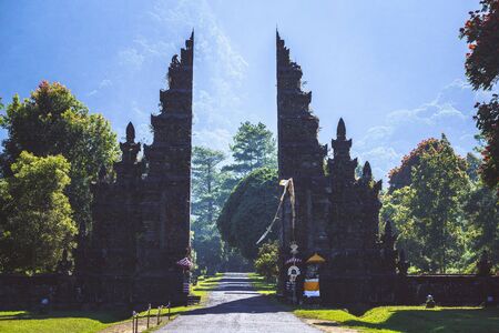 Tourist standing at traditional Hindu temples gate (Gapura Handara Kosaido) on the north of Bali island, Indonesiaの写真素材
