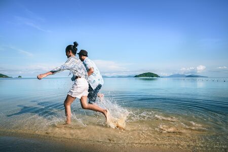 Asian teenage girl and boy running on the beach, Koh Mak Thailandの写真素材