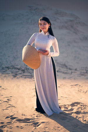 Beautiful vietnamese lady with vietnam culture traditional dress standing at a white sand Mui ne, Ho Chi Minh City Vietnamの写真素材