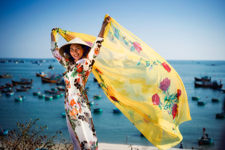 Vietnamese lady with Ao Dai Vietnam traditional dress and conical hat wait at the harbor, Fishing Harbour Mui Ne Vietnamの写真素材