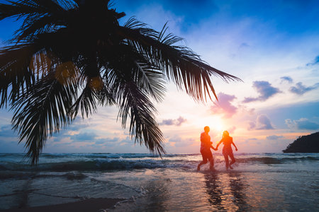 Teenage couple running on the beach at sunset, Ko Kut Thailandの写真素材