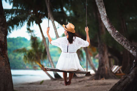 Female tourist sitting on swing at the beach, Ko Kut Thailandの写真素材